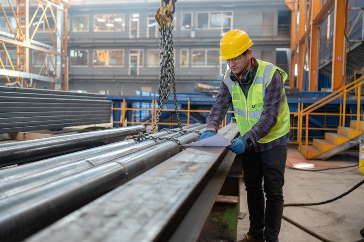 A worker is inspecting stainless steel pipes in a factory in Philadelphia, PA
