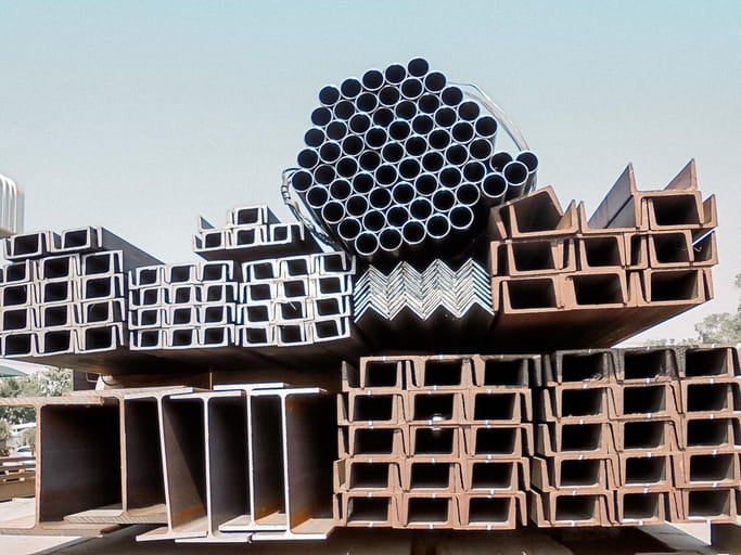 Stacked steel beams and pipes in an outdoor storage yard in Philadelphia, PA